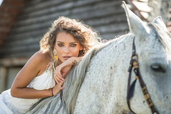 巻き毛と馬を持つ美しいブロンドの女性 白いドレスと馬の少女の肖像画 美しい女の子が交流し 牧場で馬と楽しい時間を過ごしています — ストック写真