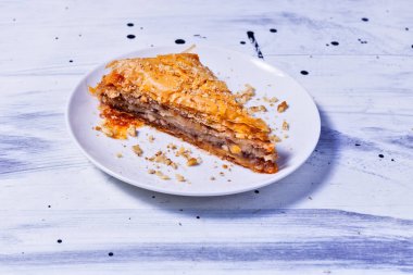 Beyaz bir tabakta tatlı olarak tek parça Yunan baklavası.
