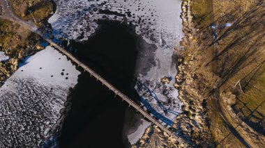 Eski, ahşap, donmuş nehirde küçük bir köprü, güneşli, serin bir gün. hava görünümü