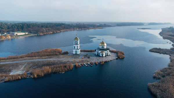 Aerial view of the old Church of the Transfiguration with a bell tower on the island of the Kanev reservoir, the flooded village of Gusintsy, Rzhishchev, Ukraine.