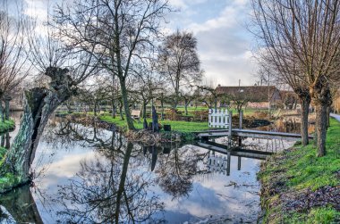 Vllist, The Netherlands, Januari 9, 2022: pollard willows and other trees reflecting in the water of a side channel of the Vlist river