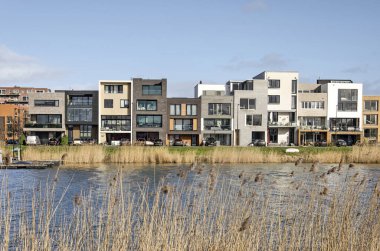 Amsterdam, Hollanda, 11 Şubat 2022: Sazlıklarla kaplı bir göl boyunca renkli ve farklı rıhtımlara doğru bakın.