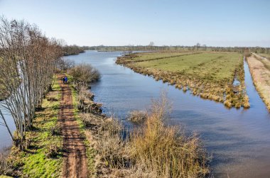 Hollanda 'nın çimen, kanallar, sazlıklar, çalılar ve Hollanda' nın Krimpenerwaard bölgesinde baharın başlarında güneşli bir günde yürüyüş parkurunun hava manzarası
