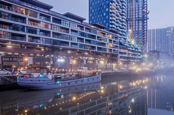 Rotterdam, Hollanda, 12 Ocak 2022: kısmen yapım aşamasında olan modern konut binaları ve tarihi gemiler sisli bir sabahta Wijnhaven limanının durgun sularına yansıyor.