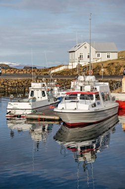 Stykkisholmur, Iceland, May 4, 2022: a calm day in springtime with boats reflecting in the water of the town's harbour