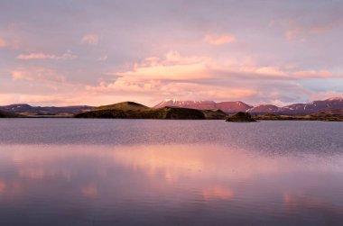 Dağlarla, tepelerle ve kraterlerle dolu manzara muhteşem bir gökyüzü altında Myvatn, İzlanda gölüne yansıyor.