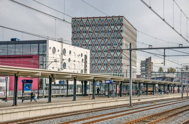 Gouda, Hollanda, 16 Kasım 2019: Arka planda sinema ve kasaba ofisi bulunan yerel tren istasyonundaki raylar ve platform