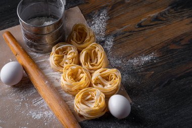 Yuva şeklinde katlanmış ev yapımı fettucine makarna. Ev yapımı geleneksel İtalyan fettuccine makarna malzemeleriyle ev yemeği..