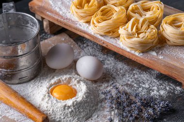 Yuva şeklinde katlanmış ev yapımı fettucine makarna. Ev yapımı geleneksel İtalyan fettuccine makarna malzemeleriyle ev yemeği..