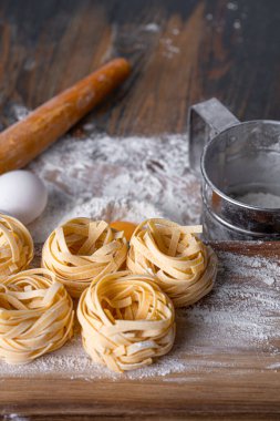 Yuva şeklinde katlanmış ev yapımı fettucine makarna. Ev yapımı geleneksel İtalyan fettuccine makarna malzemeleriyle ev yemeği..