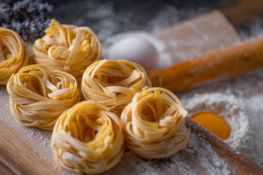 Yuva şeklinde katlanmış ev yapımı fettucine makarna. Ev yapımı geleneksel İtalyan fettuccine makarna malzemeleriyle ev yemeği..