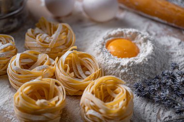 Yuva şeklinde katlanmış ev yapımı fettucine makarna. Ev yapımı geleneksel İtalyan fettuccine makarna malzemeleriyle ev yemeği..