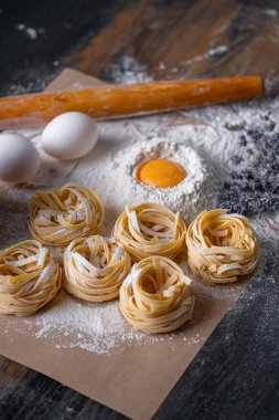 Yuva şeklinde katlanmış ev yapımı fettucine makarna. Ev yapımı geleneksel İtalyan fettuccine makarna malzemeleriyle ev yemeği..