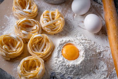 Yuva şeklinde katlanmış ev yapımı fettucine makarna. Ev yapımı geleneksel İtalyan fettuccine makarna malzemeleriyle ev yemeği..