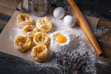 Yuva şeklinde katlanmış ev yapımı fettucine makarna. Ev yapımı geleneksel İtalyan fettuccine makarna malzemeleriyle ev yemeği..