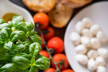 Masanın üzerinde aromatik domatesli taze fesleğen ve İtalyan mozzarellası var. Bruschetta ve zeytinyağının yanında Provencal otlar var.