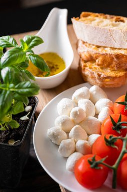 Masanın üzerinde aromatik domatesli taze fesleğen ve İtalyan mozzarellası var. Bruschetta ve zeytinyağının yanında Provencal otlar var.