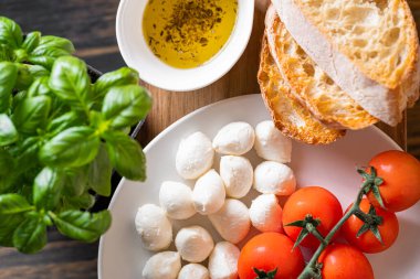 Masanın üzerinde aromatik domatesli taze fesleğen ve İtalyan mozzarellası var. Bruschetta ve zeytinyağının yanında Provencal otlar var.