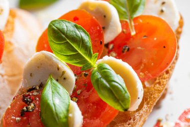 bruschetta caprese. Taze fesleğen yaprakları, olgun aromatik domatesler ve bruschetta üzerine İtalyan mozzarella, zeytin yağı serpiştirilmiş ve biber ve bitkilerle serpilmiş..