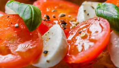 bruschetta caprese. Taze fesleğen yaprakları, olgun aromatik domatesler ve bruschetta üzerine İtalyan mozzarella, zeytin yağı serpiştirilmiş ve biber ve bitkilerle serpilmiş..