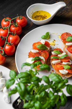 bruschetta caprese. Taze fesleğen yaprakları, olgun aromatik domatesler ve bruschetta üzerine İtalyan mozzarella, zeytin yağı serpiştirilmiş ve biber ve bitkilerle serpilmiş..