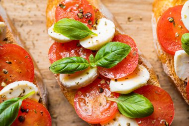 bruschetta caprese. Taze fesleğen yaprakları, olgun aromatik domatesler ve bruschetta üzerine İtalyan mozzarella, zeytin yağı serpiştirilmiş ve biber ve bitkilerle serpilmiş..