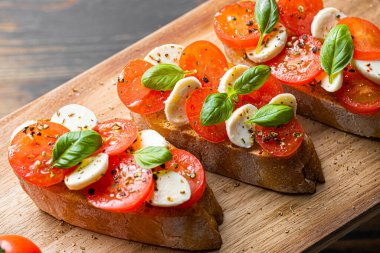 bruschetta caprese. Taze fesleğen yaprakları, olgun aromatik domatesler ve bruschetta üzerine İtalyan mozzarella, zeytin yağı serpiştirilmiş ve biber ve bitkilerle serpilmiş..