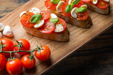 bruschetta caprese. Taze fesleğen yaprakları, olgun aromatik domatesler ve bruschetta üzerine İtalyan mozzarella, zeytin yağı serpiştirilmiş ve biber ve bitkilerle serpilmiş..
