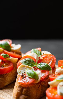bruschetta caprese. Taze fesleğen yaprakları, olgun aromatik domatesler ve bruschetta üzerine İtalyan mozzarella, zeytin yağı serpiştirilmiş ve biber ve bitkilerle serpilmiş..