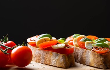 bruschetta caprese. Taze fesleğen yaprakları, olgun aromatik domatesler ve bruschetta üzerine İtalyan mozzarella, zeytin yağı serpiştirilmiş ve biber ve bitkilerle serpilmiş..