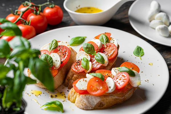 bruschetta caprese. Taze fesleğen yaprakları, olgun aromatik domatesler ve bruschetta üzerine İtalyan mozzarella, zeytin yağı serpiştirilmiş ve biber ve bitkilerle serpilmiş..