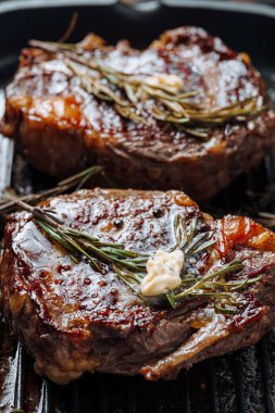 Biberiyeli tuzlu ve biberiyeli bifteğin üzerine tereyağı serpiştirilmiş ızgarada görkemli biftekler pişirmek.