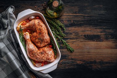 Çiğ hindi butları baharat ve tuzla ovulmuş, fırın tepsisine portakal limonlu sarımsaklı biberiye kekiği ve zeytinyağıyla birlikte. İki kişilik sağlıklı ve lezzetli bir akşam yemeği konsepti.