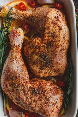 Çiğ hindi butları baharat ve tuzla ovulmuş, fırın tepsisine portakal limonlu sarımsaklı biberiye kekiği ve zeytinyağıyla birlikte. İki kişilik sağlıklı ve lezzetli bir akşam yemeği konsepti.