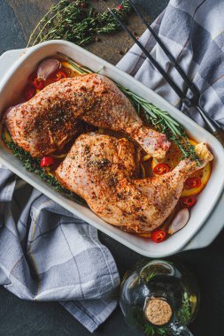 Çiğ hindi butları baharat ve tuzla ovulmuş, fırın tepsisine portakal limonlu sarımsaklı biberiye kekiği ve zeytinyağıyla birlikte. İki kişilik sağlıklı ve lezzetli bir akşam yemeği konsepti.