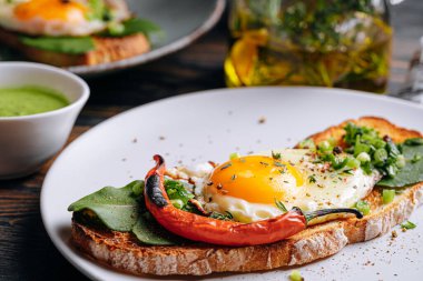 Lezzetli ve iştah açıcı bruschetta ve kahvaltıda kızarmış yumurta ve otlar.