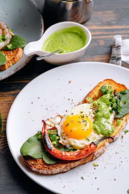 Lezzetli ve iştah açıcı bruschetta ve kahvaltıda kızarmış yumurta ve otlar.