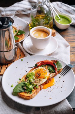 Sıcak ve yüksek kalorili kahvaltı. Lezzetli ve ağız sulandırıcı bruschetta ve kahvaltıda kızarmış yumurta ve bir fincan aromatik kahve..