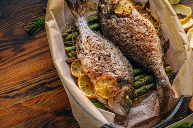 Dorado 'dan iki kişilik lezzetli bir akşam yemeği konsepti. Kuşkonmaz ve baharatlı limonlu fırında dorado balığı.