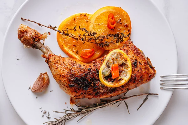 Kızarmış hindi budu, baharat ve tuzla ovulmuş, portakallar, limonlar, sarımsak, biberiye, kekik ve zeytinyağı ile pişirilmiş. İki kişilik sağlıklı ve lezzetli bir akşam yemeği konsepti.