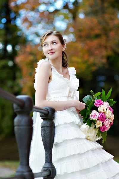 Bride in white dress with bunch of flowers — Stock Photo, Image