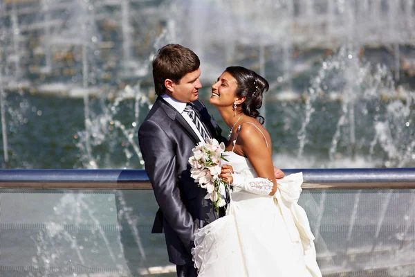 Happy bride and groom near fountain — Stock Photo, Image