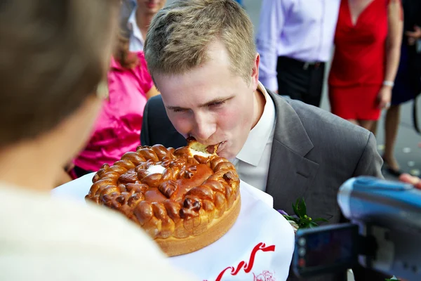 Groom bites loaf at the wedding — Stock Photo, Image