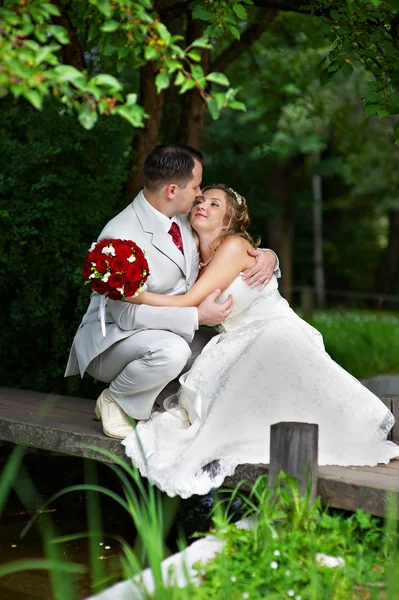 Novia y novio en un puente de madera — Foto de Stock