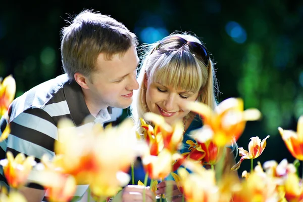 Glückliche Frau und eleganter Mann inmitten von Blumen — Stockfoto