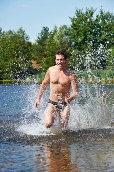 Hombre fuerte corriendo en el agua en la playa —  Fotos de Stock
