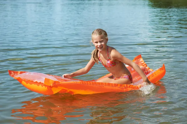 Menina feliz no colchão no lago — Fotografia de Stock