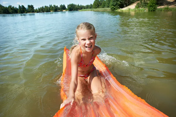 Joyful little girl on mattress in lake — Stock Photo, Image