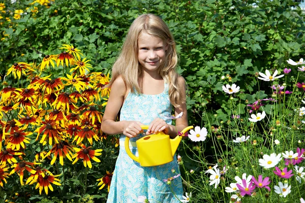 Little girl with watering can near flowers — Stock Photo, Image