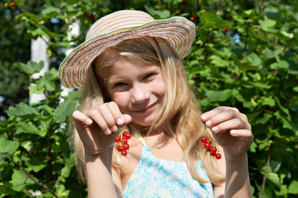 Красивая маленькая девочка с кучей красной смородины — стоковое фото